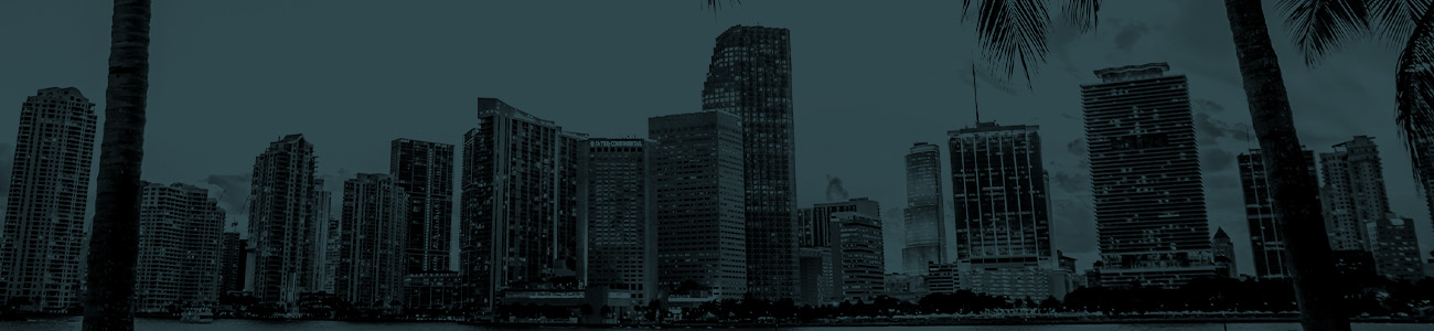 A city skyline featuring tall buildings, with palm trees prominently displayed in the foreground.