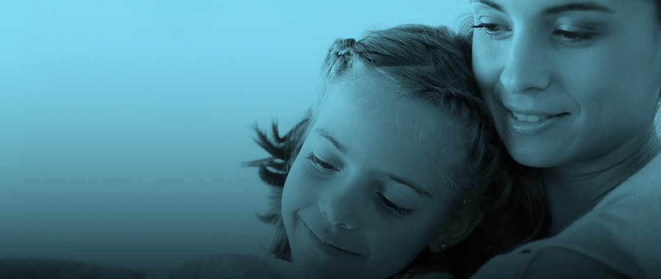 A little girl is lying on a bed, looking relaxed and content, with soft bedding surrounding her.
